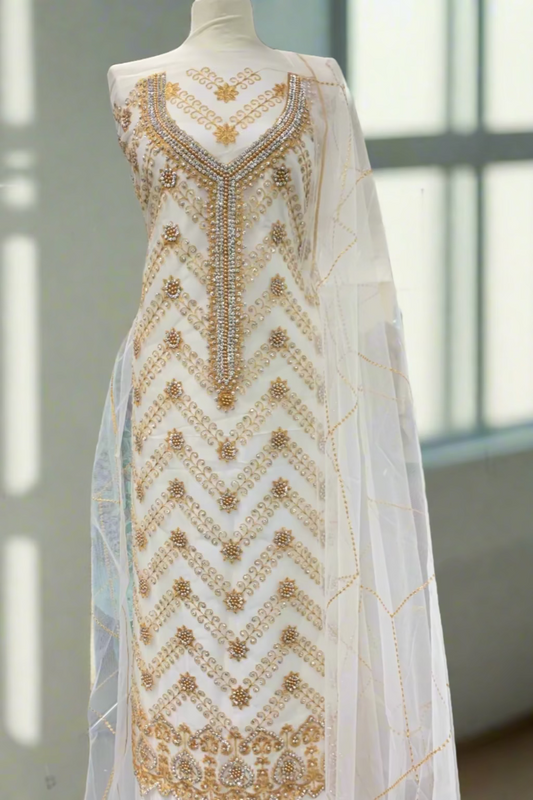 Mannequin wearing a white dress with gold embroidery in a store setting
