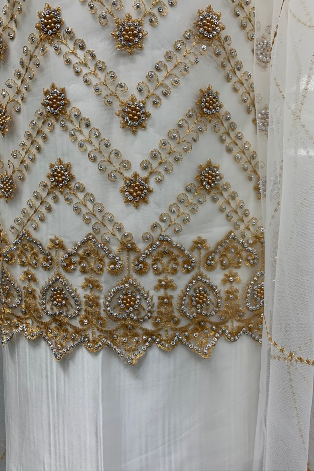 Close-up of a white fabric with intricate gold embroidery