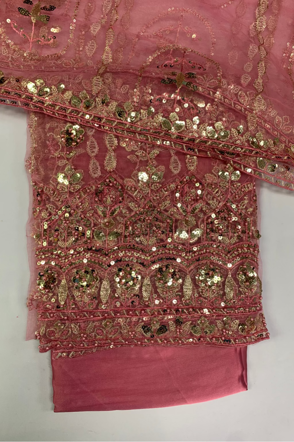 Pink fabric with gold embroidery on a white background