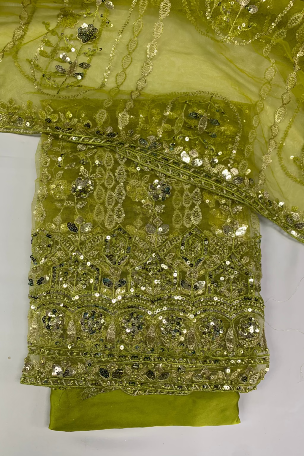 Green fabric with intricate gold embroidery on a white background