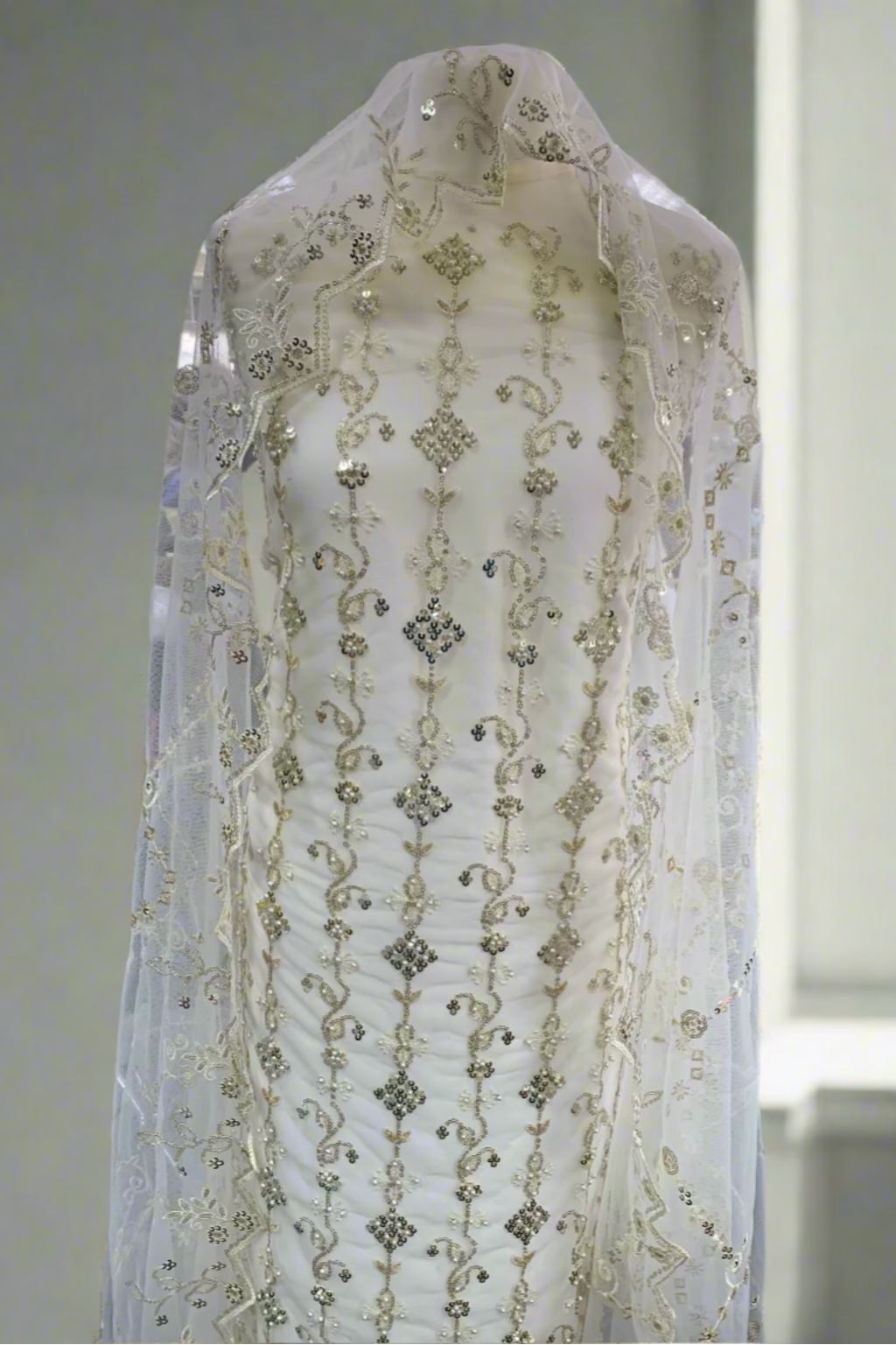 White embroidered fabric on a mannequin in a store setting