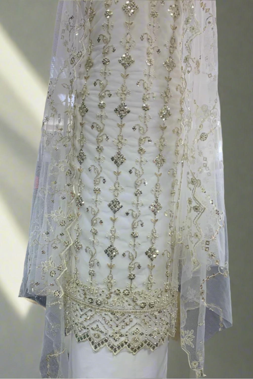 Elegant white embroidered dress on a mannequin in a store setting