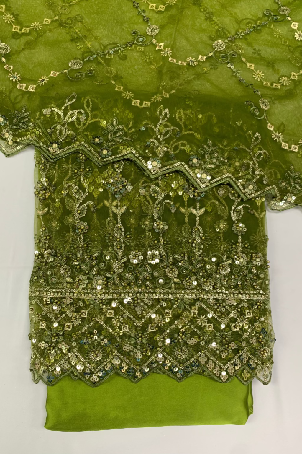 Green fabric with intricate gold embroidery on a white background