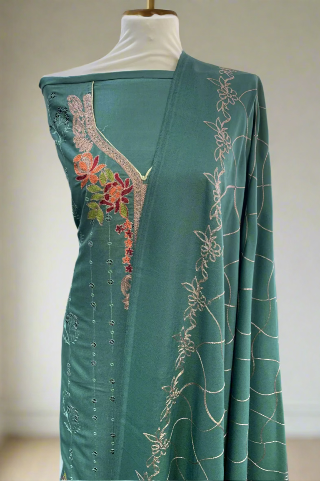 Green embroidered garment on a mannequin in a fabric store