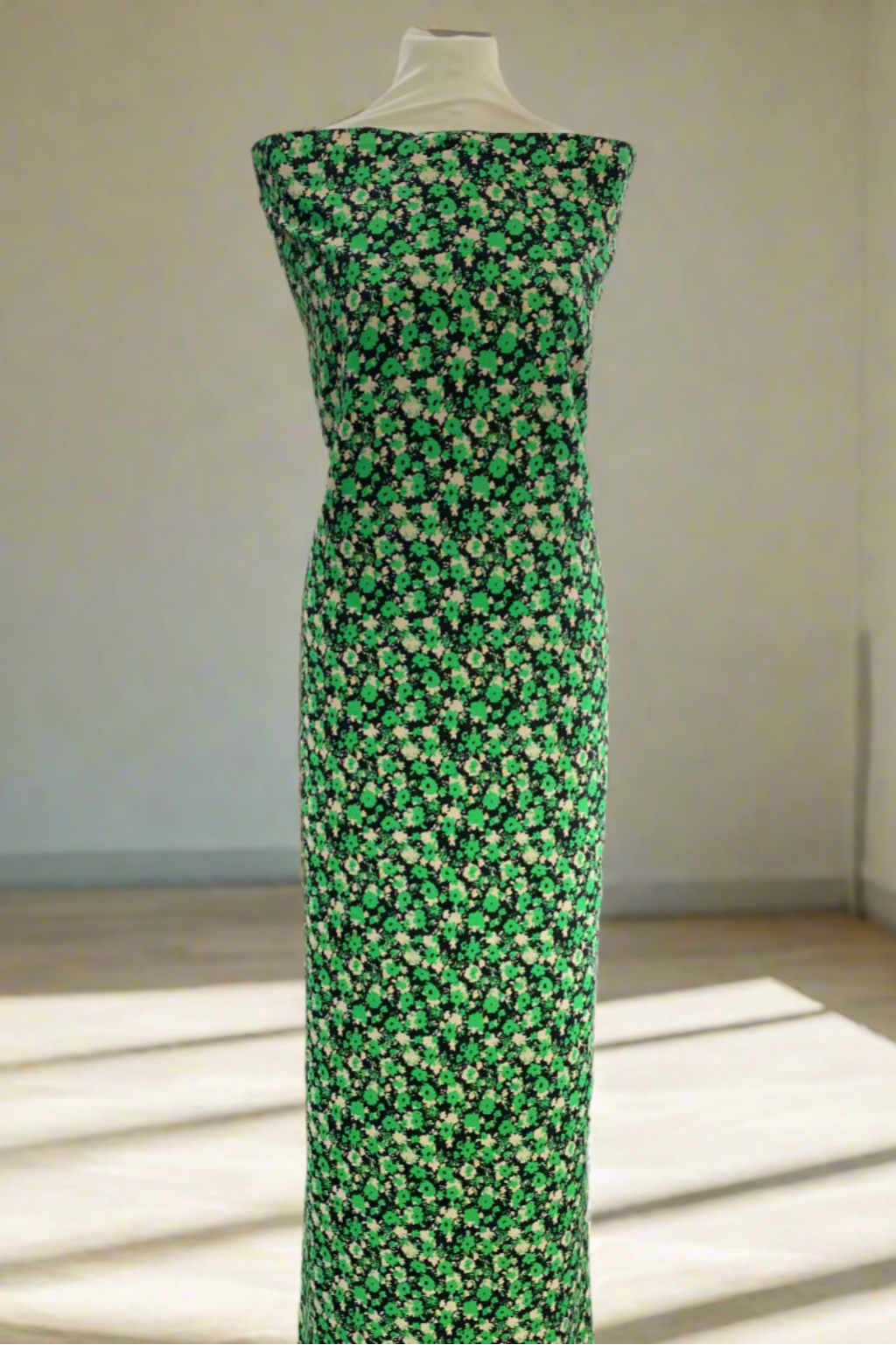 Mannequin wearing a green floral dress in a store setting