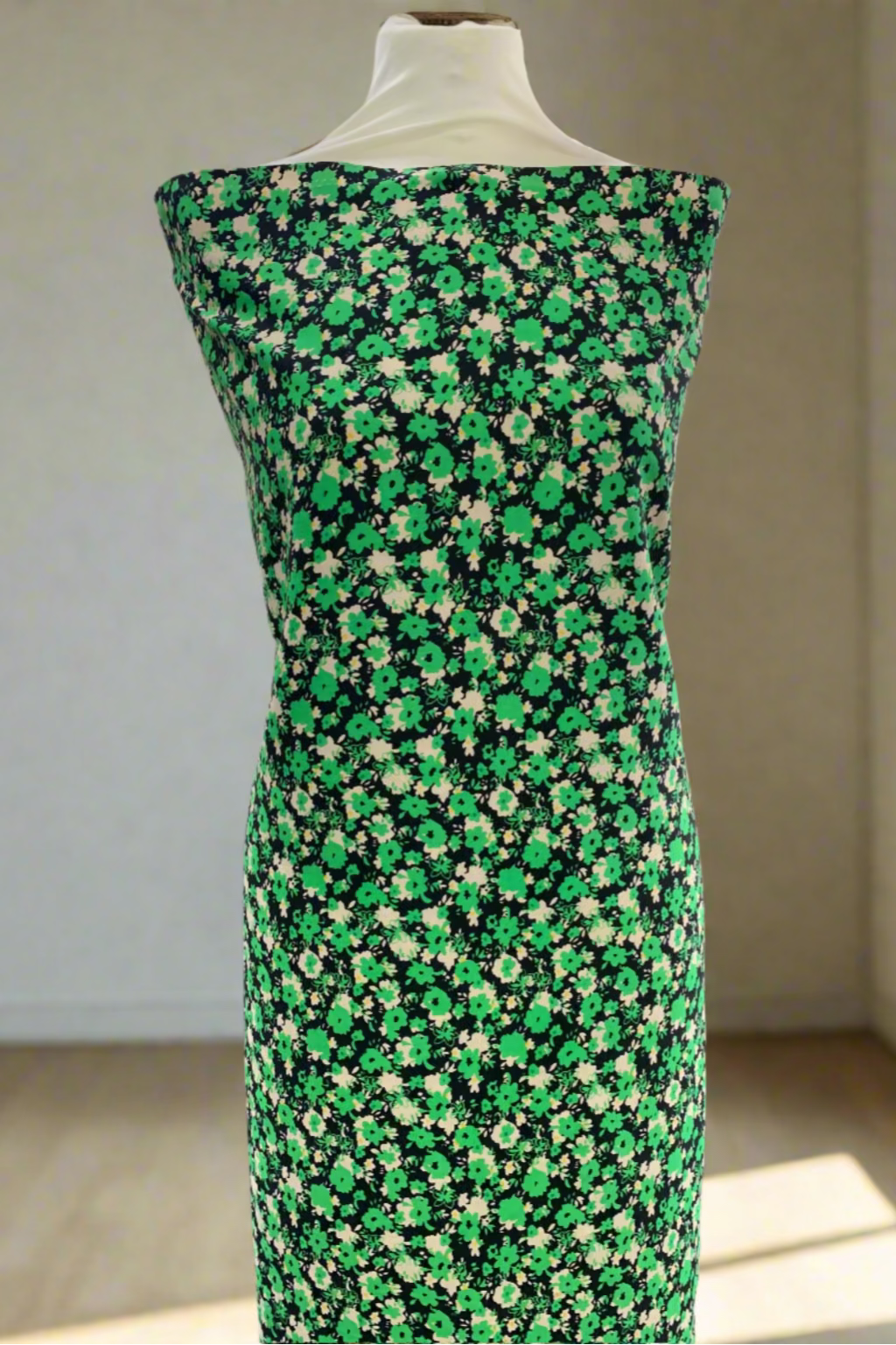 Mannequin wearing a green floral dress in a store setting