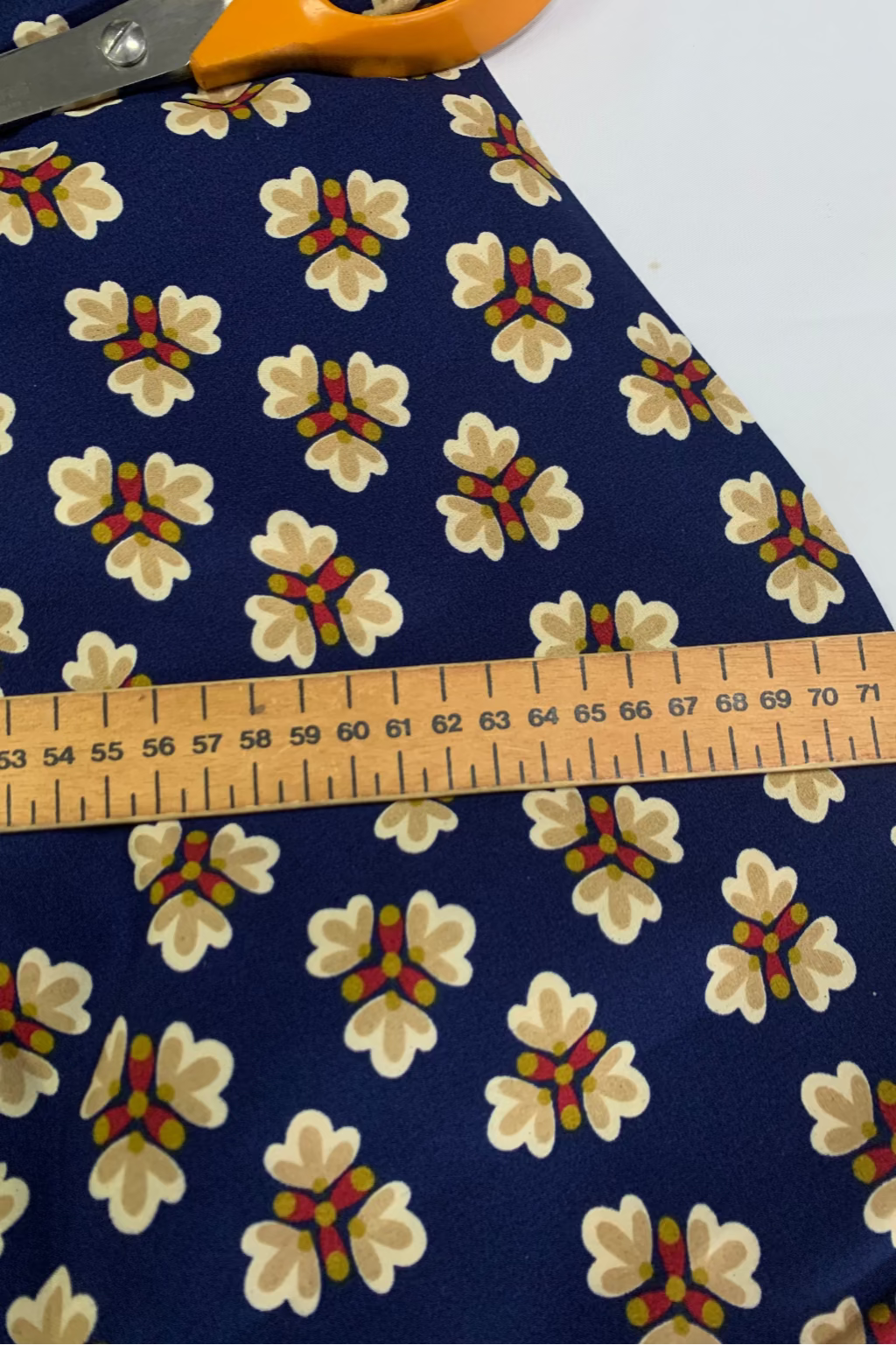 Floral-patterned fabric with a ruler and scissors on a white background