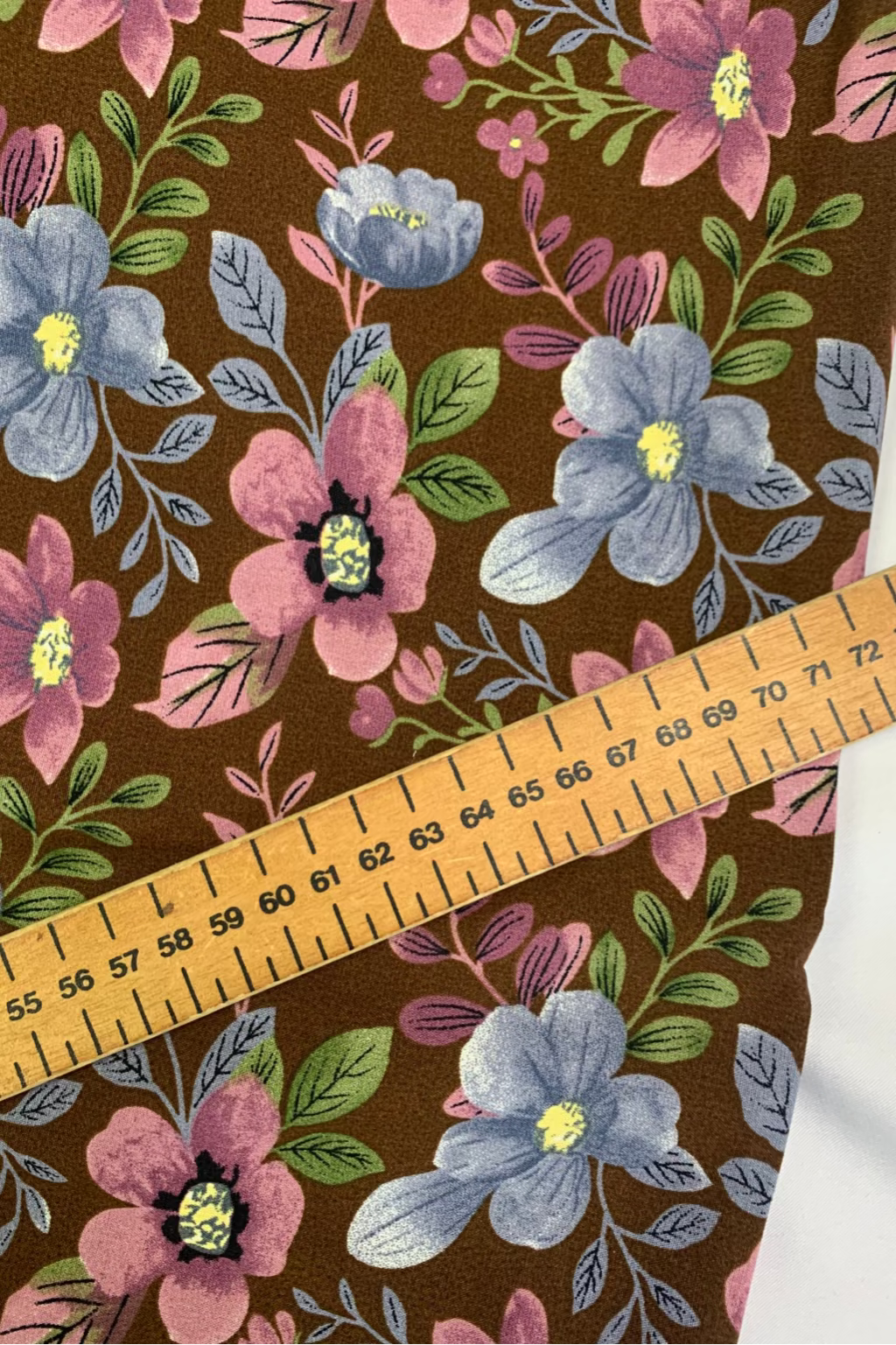 Floral fabric pattern with a ruler for scale on a brown background