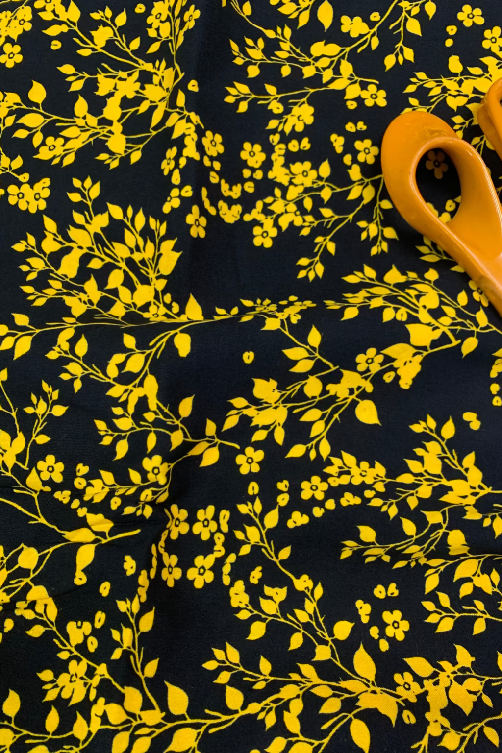 Yellow floral pattern on black fabric with a pair of scissors.