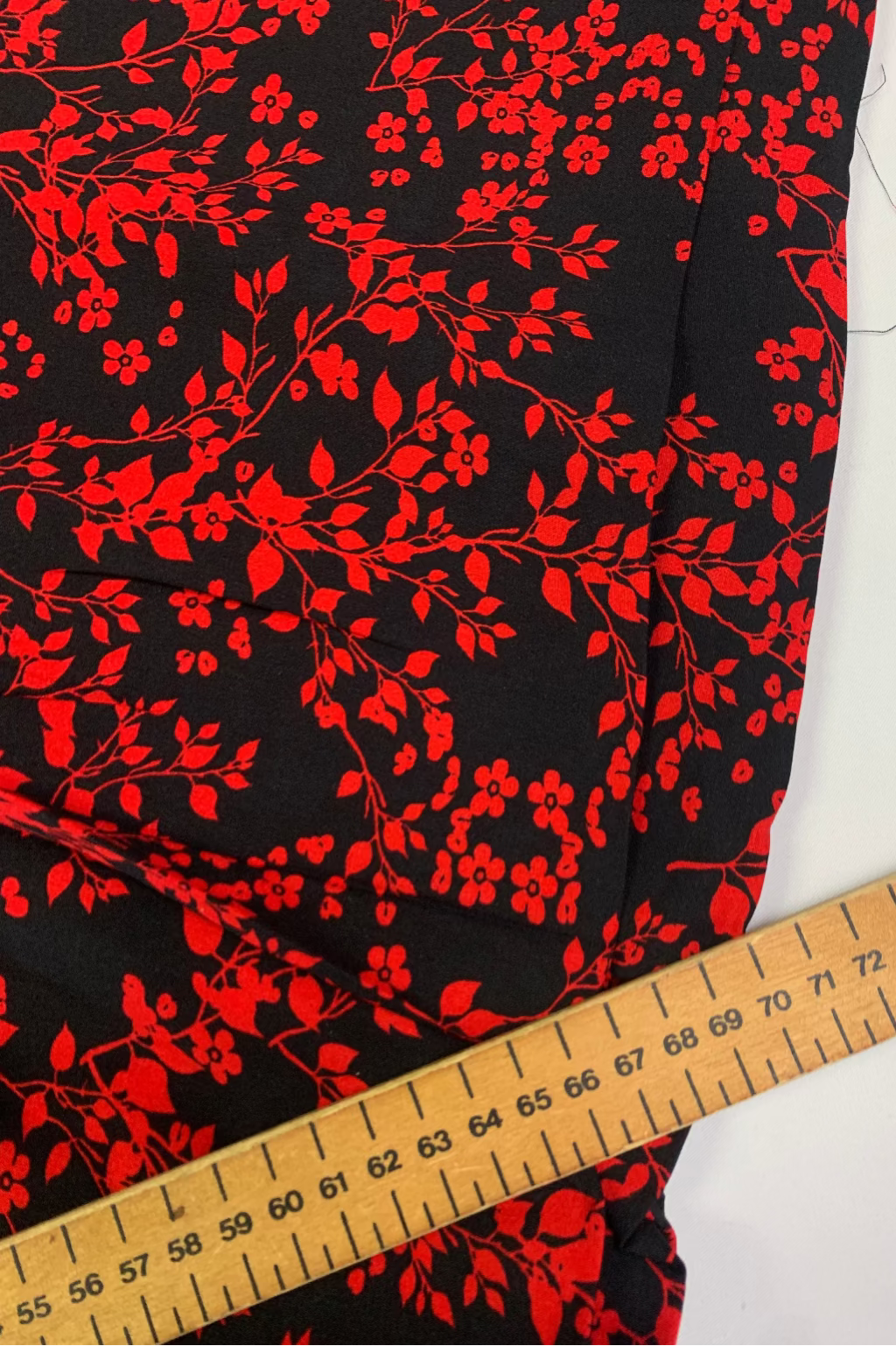 Red floral pattern on black fabric with a ruler for scale.