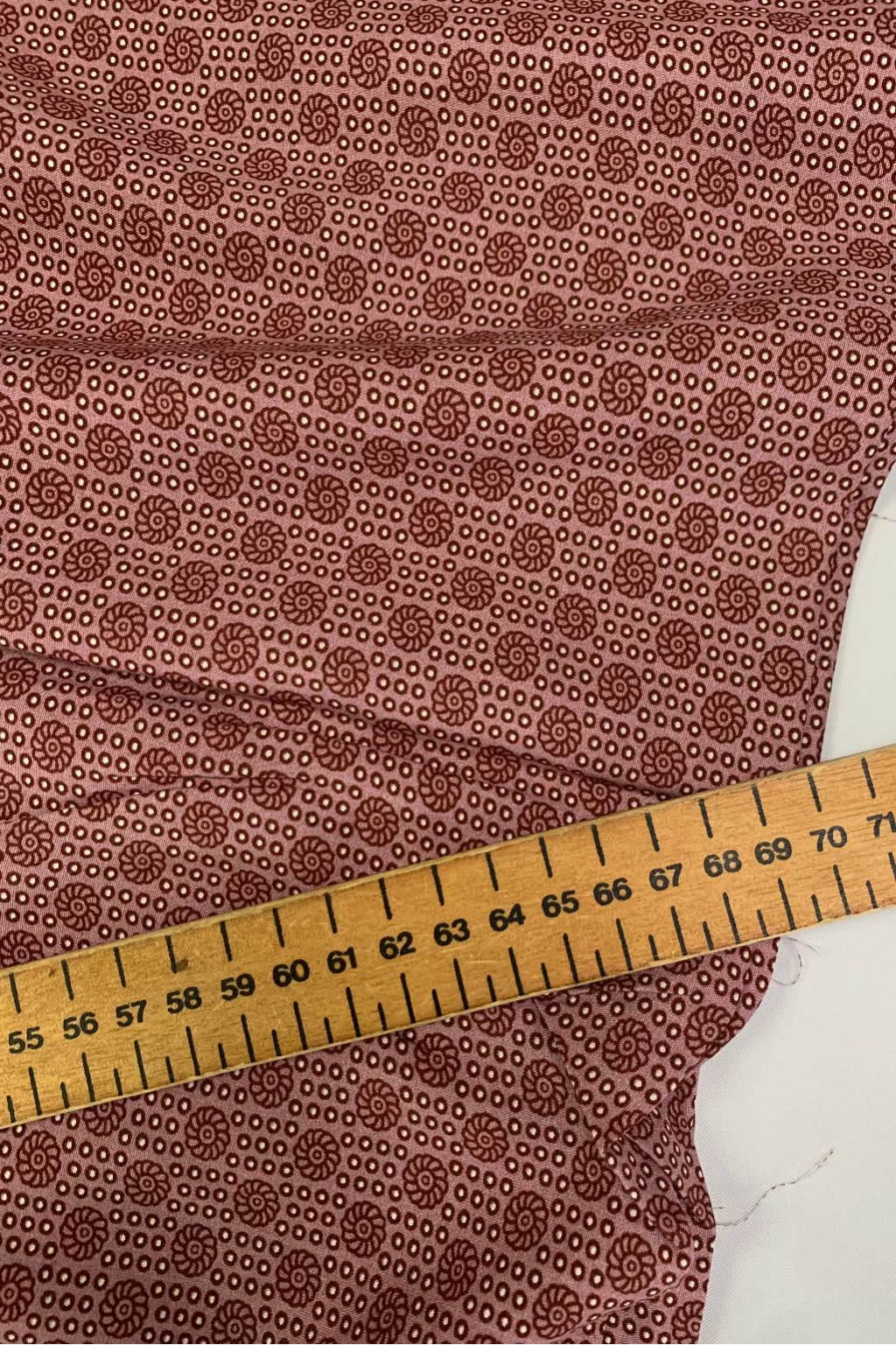 Soft pink fabric with a subtle pattern and a wooden measuring ruler on top