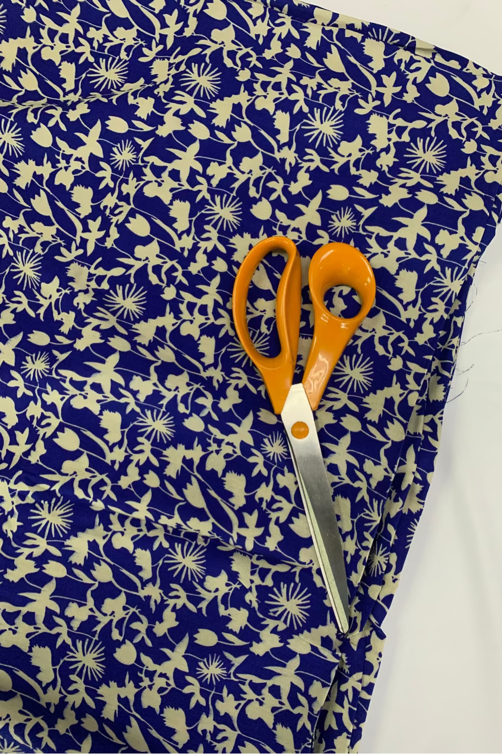 Scissors on a piece of blue fabric with white floral patterns