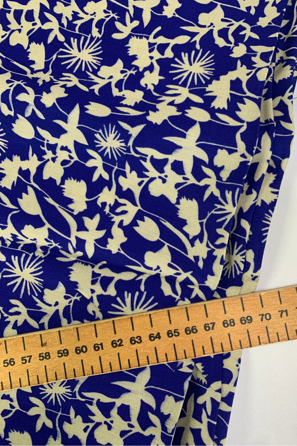 Blue fabric with white floral pattern and a wooden ruler for scale.