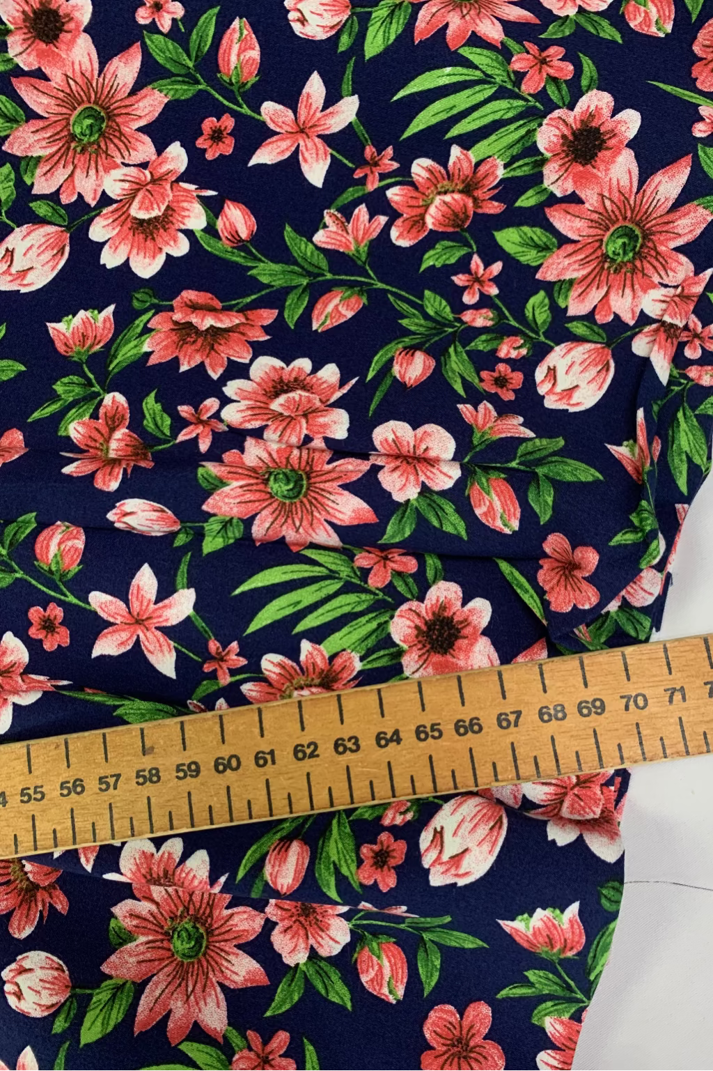 Floral fabric with pink flowers on a navy background, measured with a ruler.