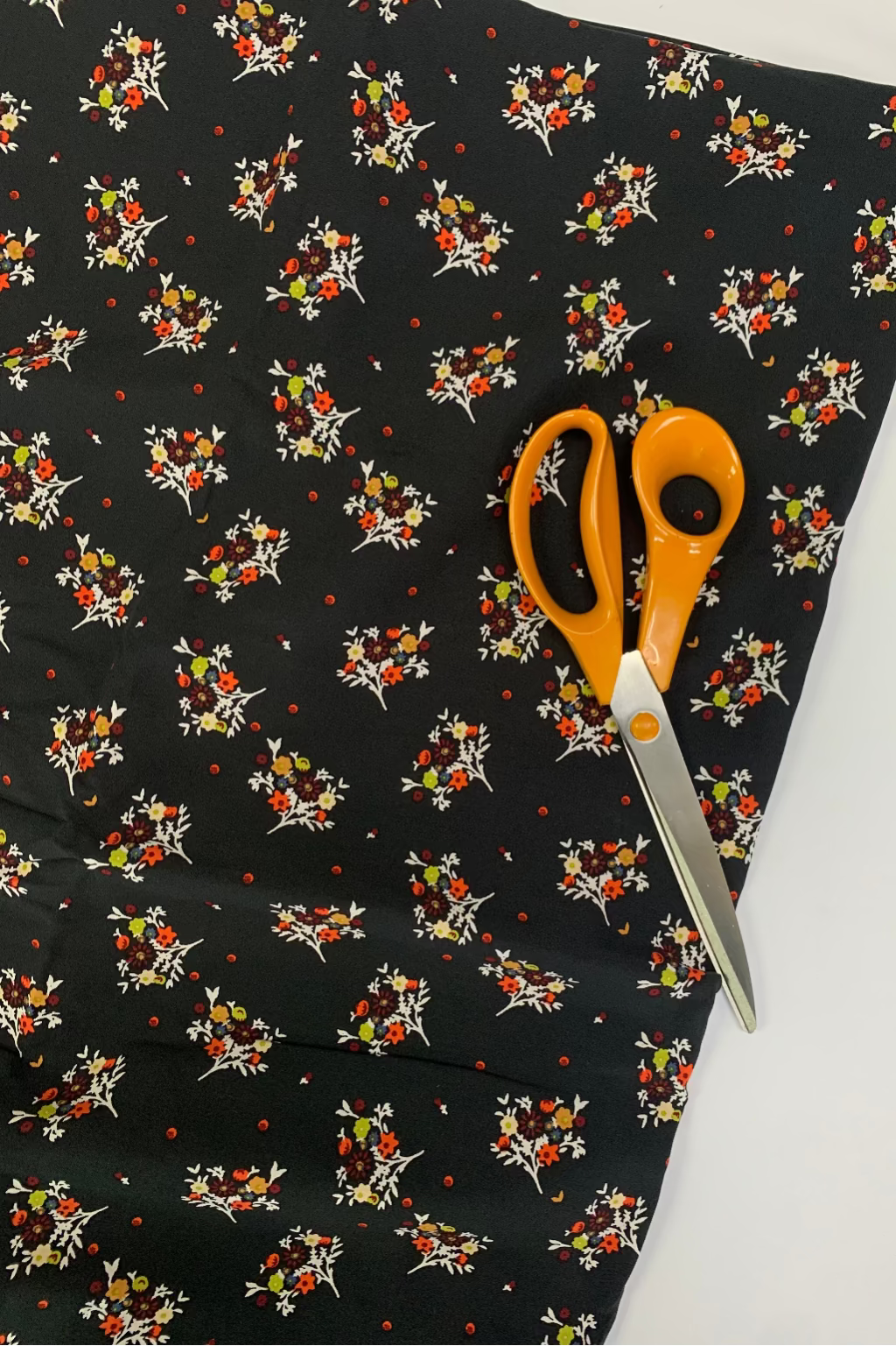 Floral-patterned fabric with scissors on a white background