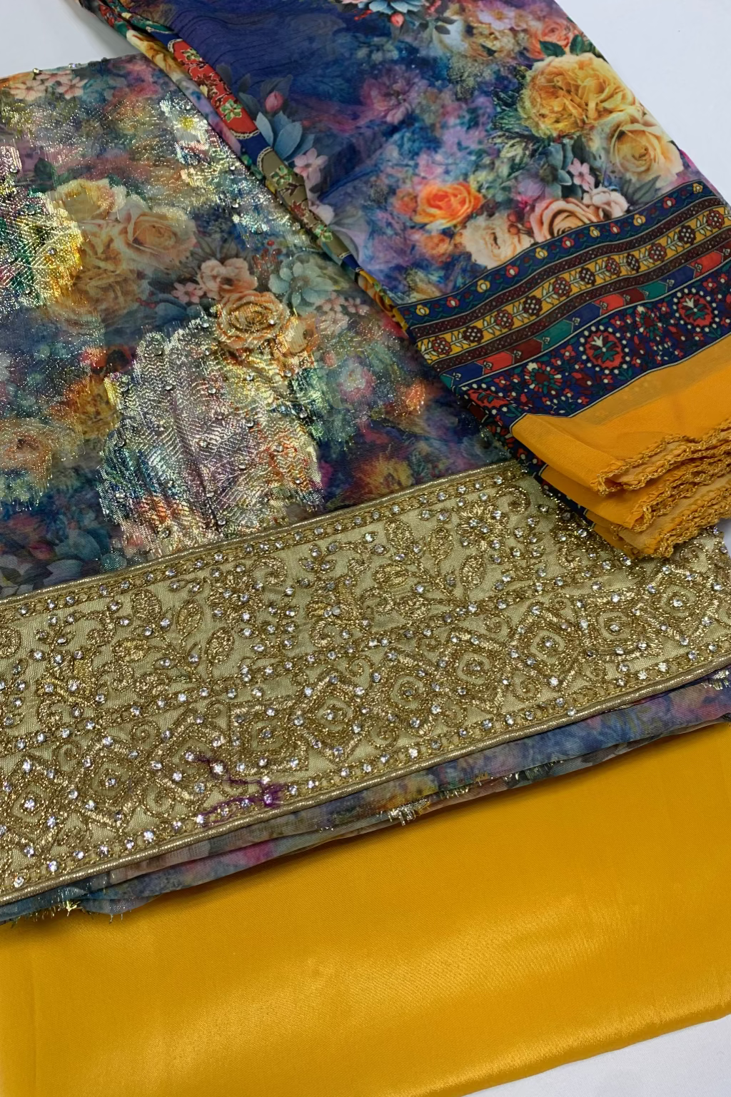 Stack of fabric with floral patterns and gold embellishments on a white background