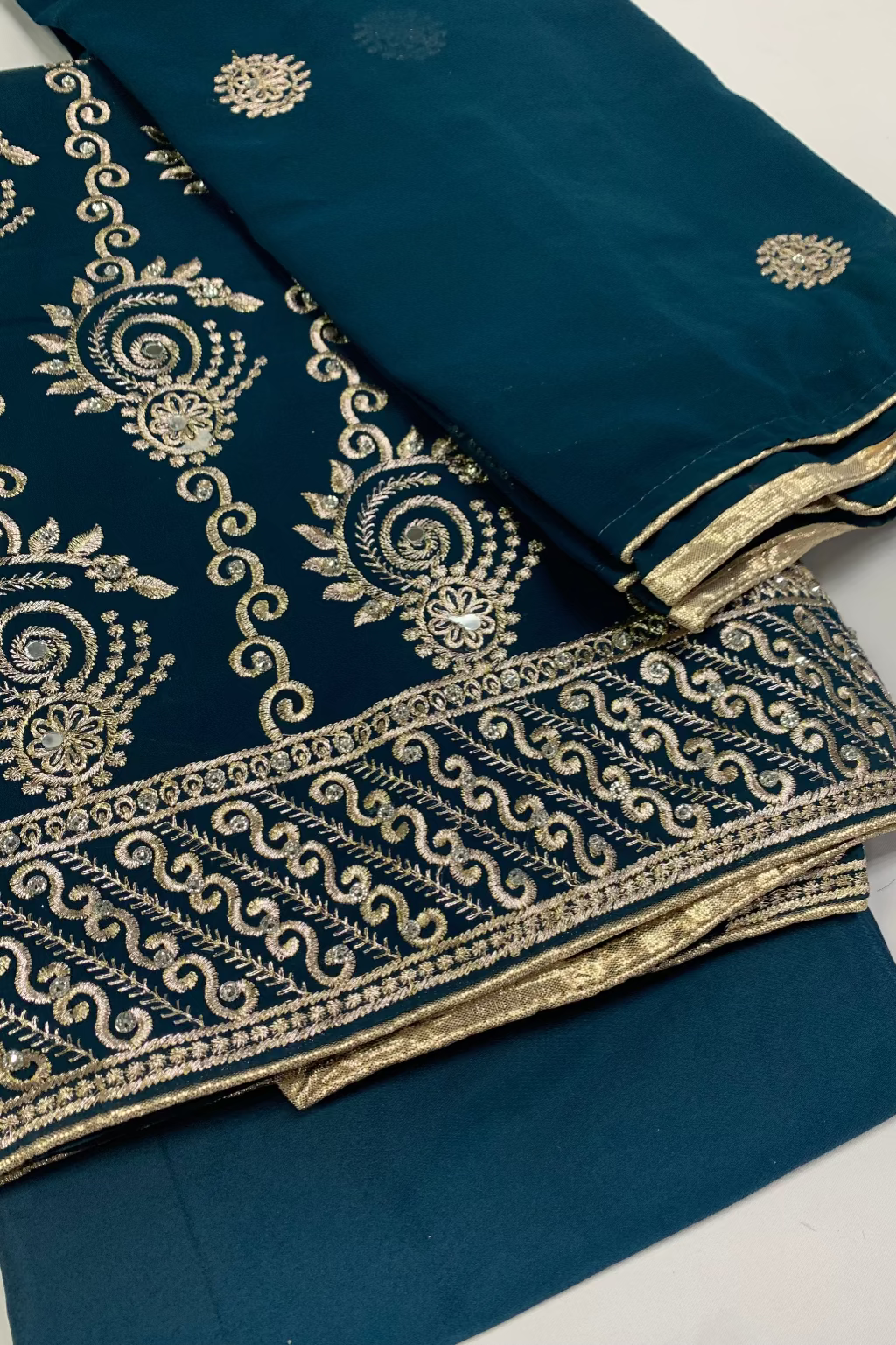 Navy blue fabric with intricate gold embroidery on a white background