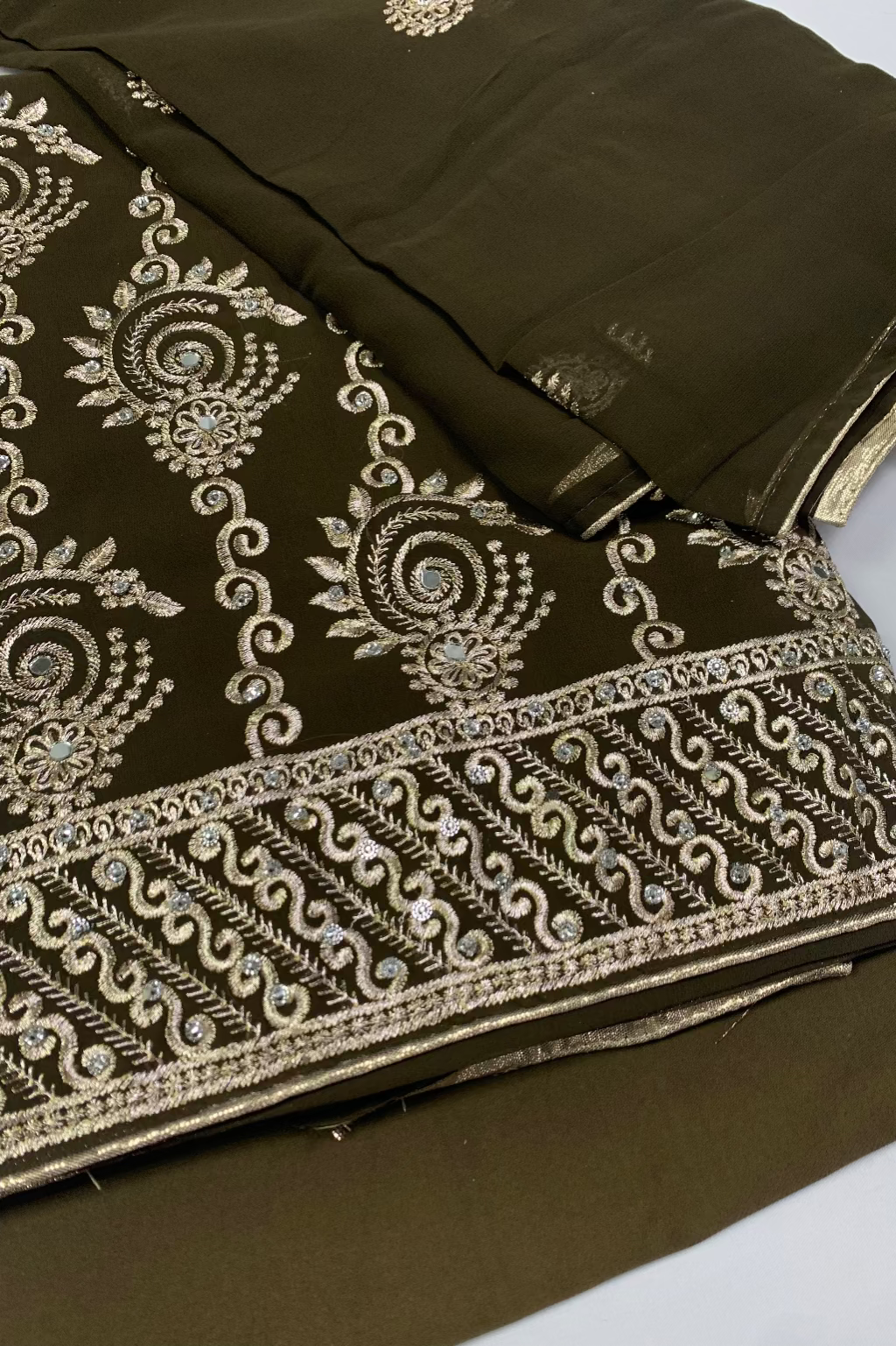 Brown fabric with intricate gold embroidery on a white background