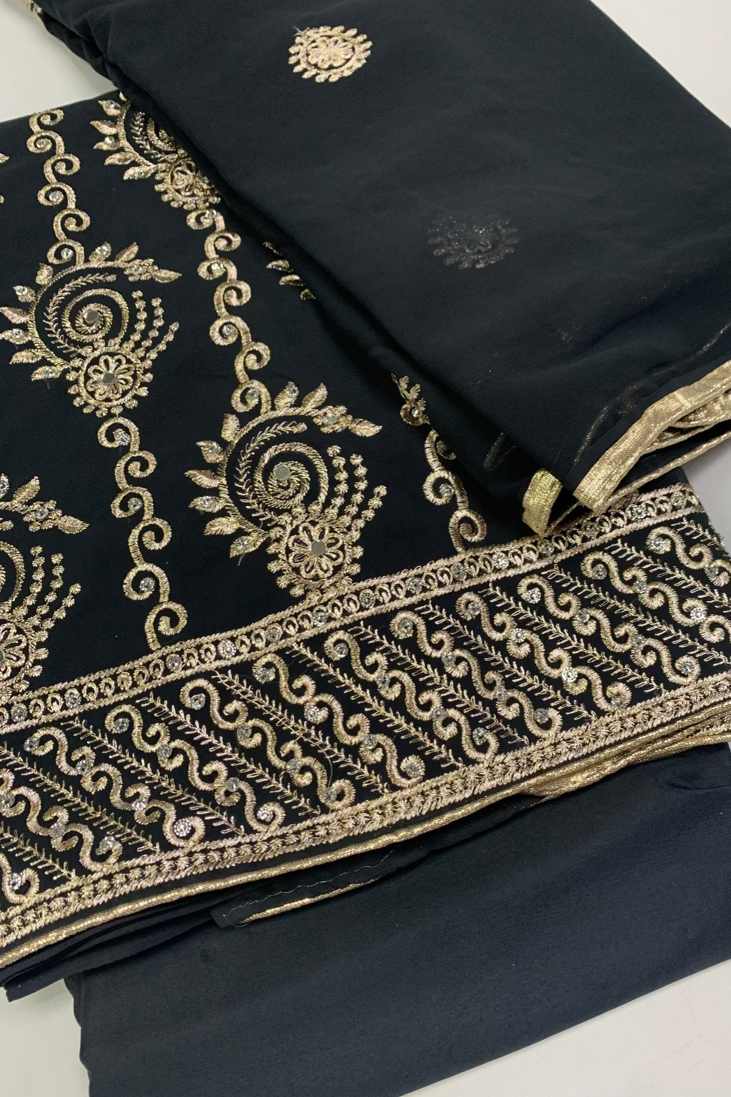 Black fabric with gold embroidery on a white background