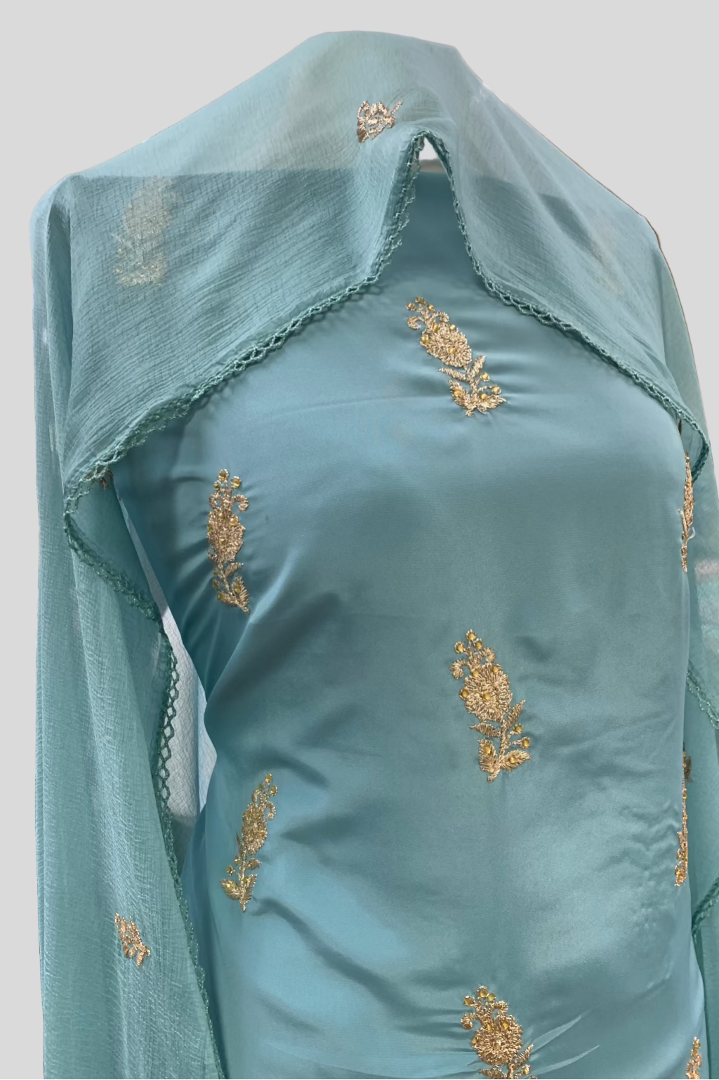 Teal fabric with gold embroidery in a store setting