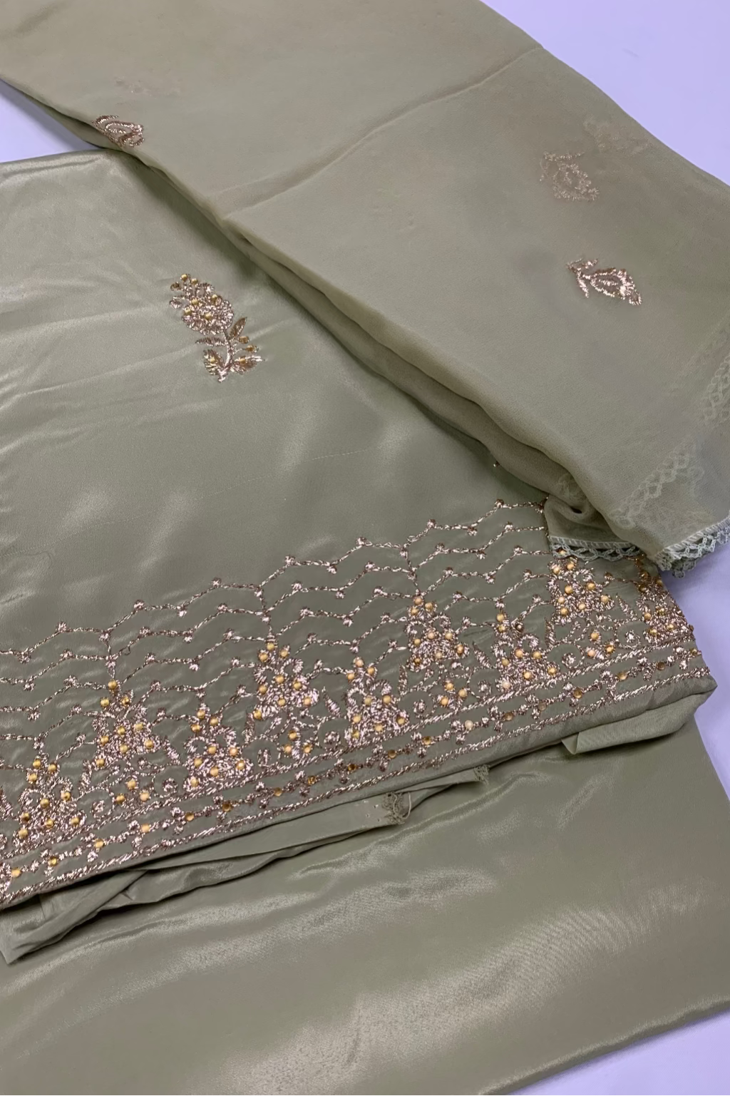 Green fabric with gold embroidery on a white background