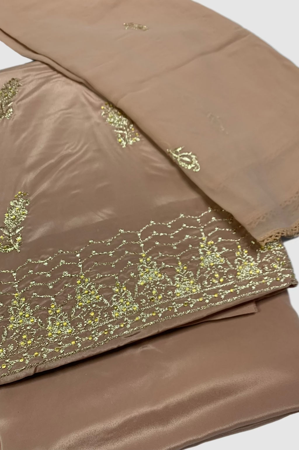 Peach fabric with gold embroidery on a white background