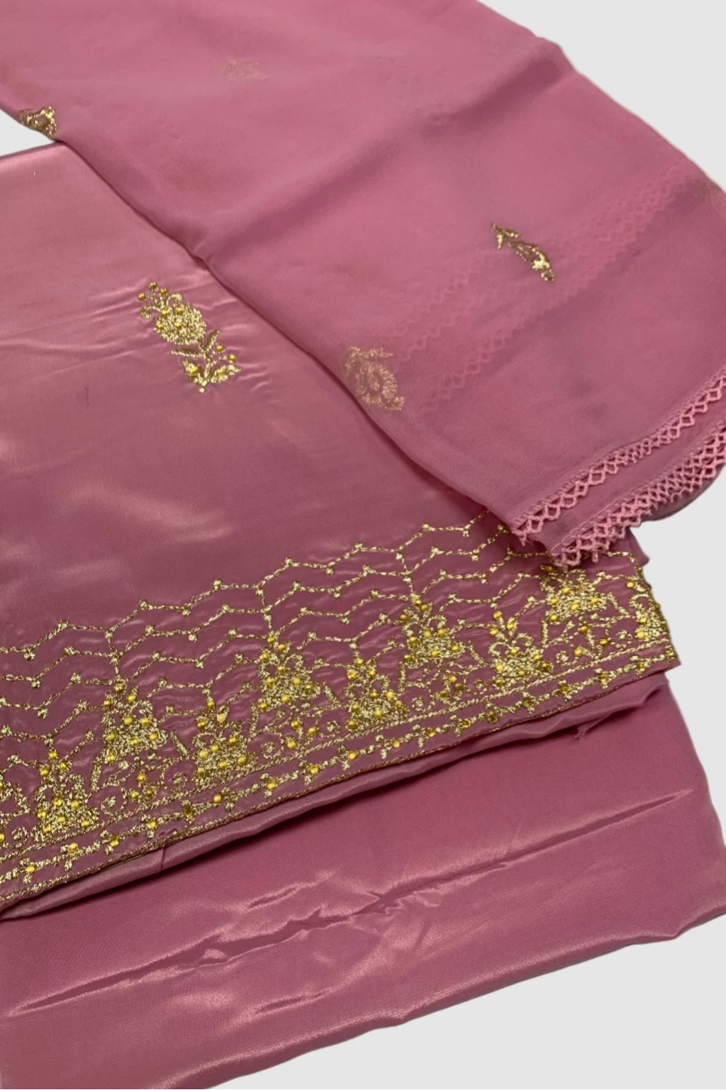 Pink fabric with gold embroidery on a white background