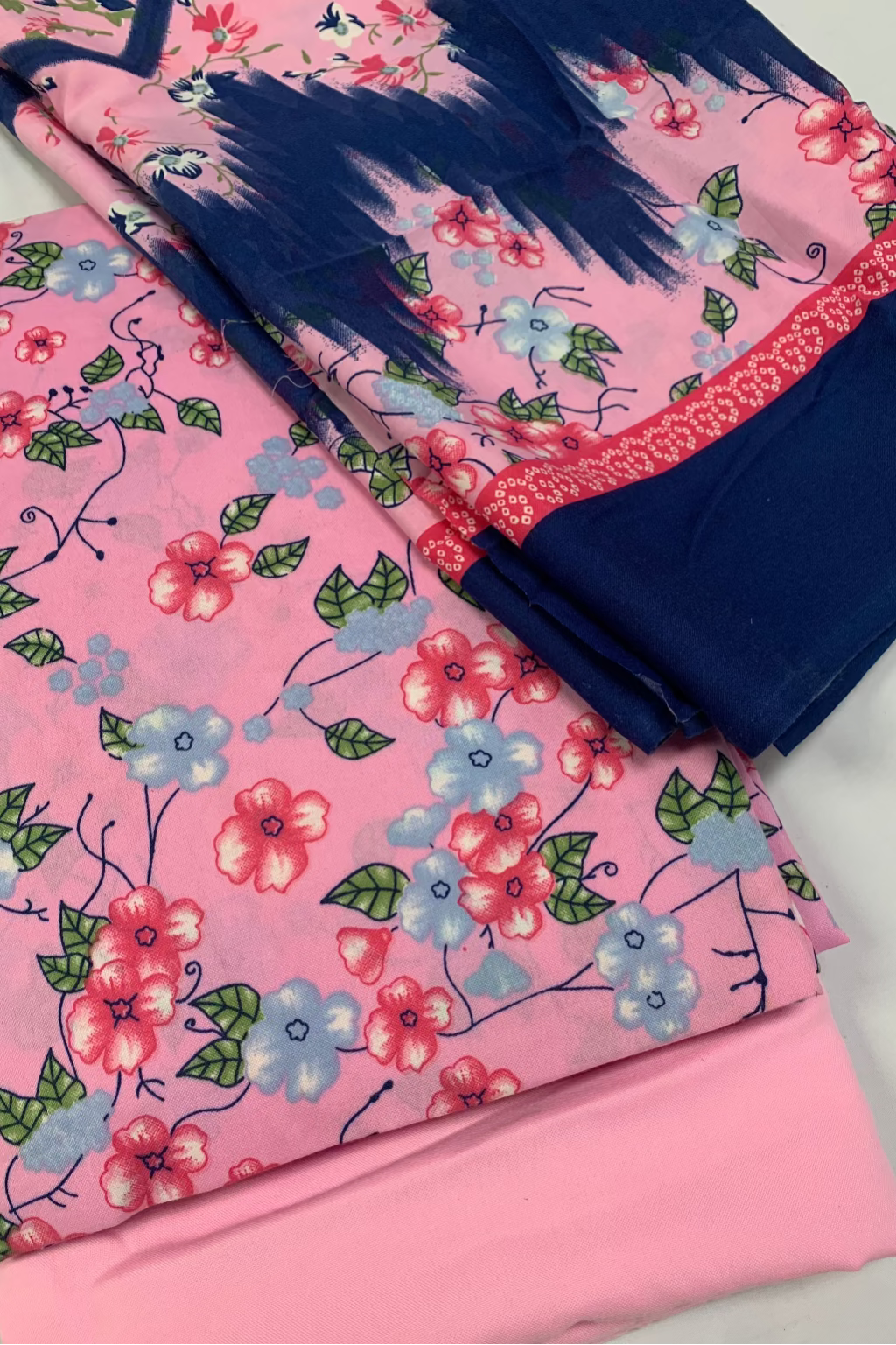 Pink fabric with floral pattern and blue fabric with fringes on a white background