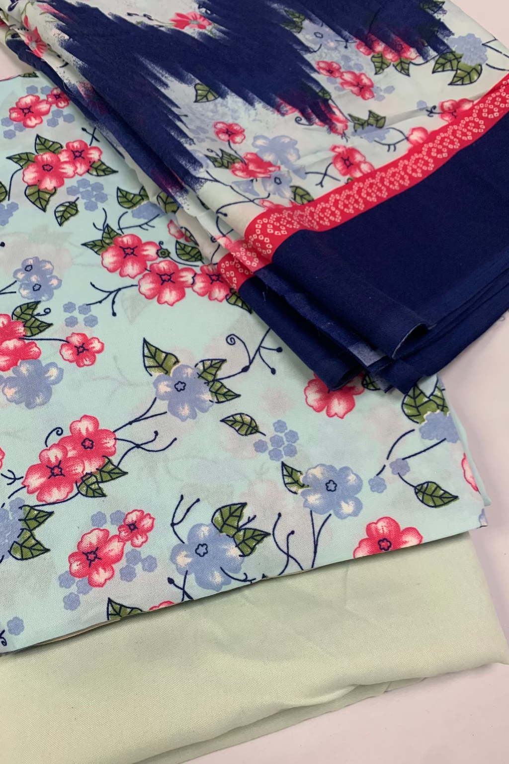 Fabric with floral pattern and solid color swatches on a light background
