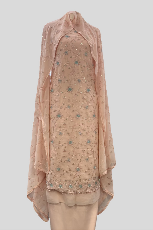 Peach embroidered traditional outfit on a mannequin in a store setting