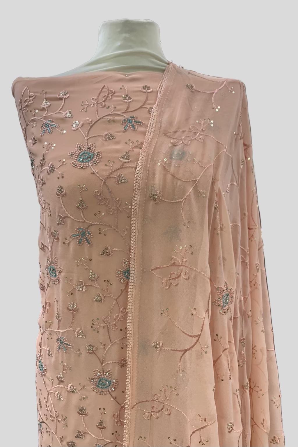 Peach embroidered fabric on a mannequin in an indoor setting