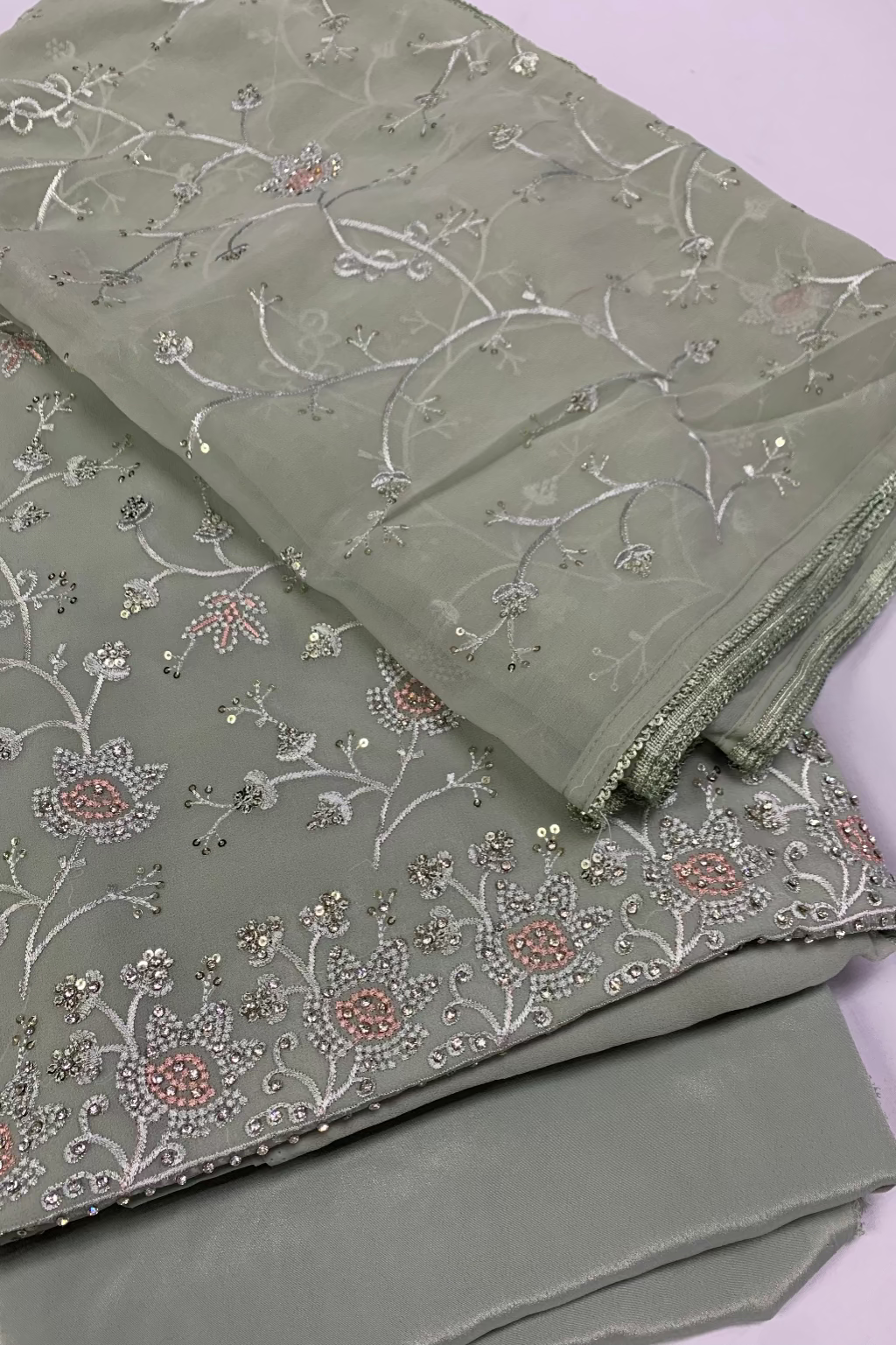 Green fabric with floral embroidery on a white background