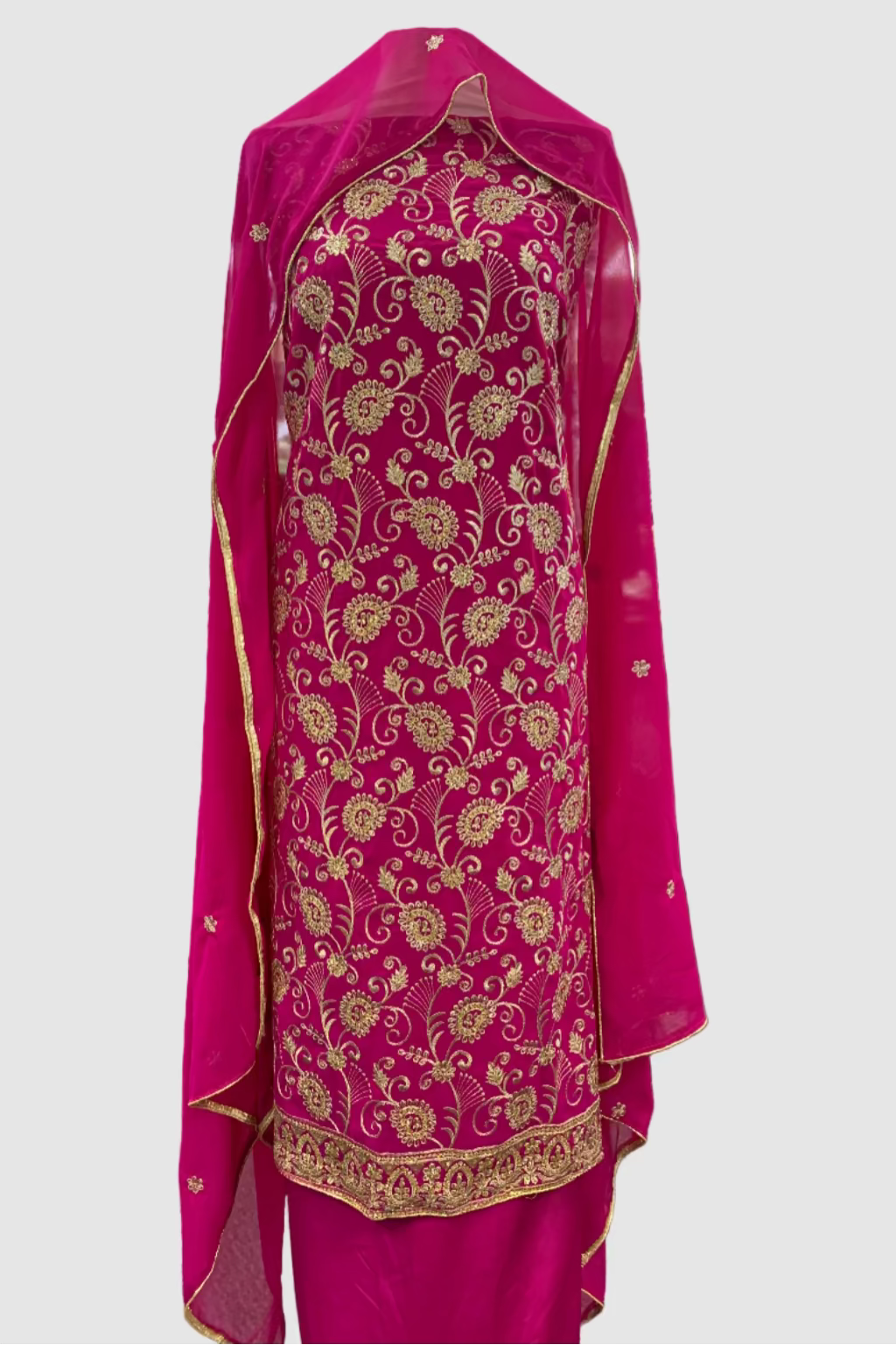 Pink embroidered traditional outfit on a hanger in a store setting