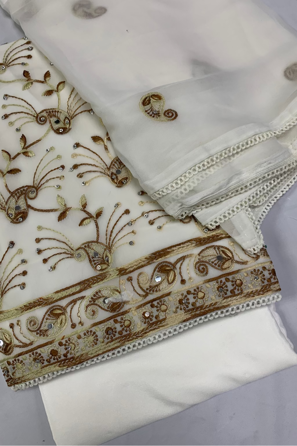 White fabric with brown embroidery on a gray background