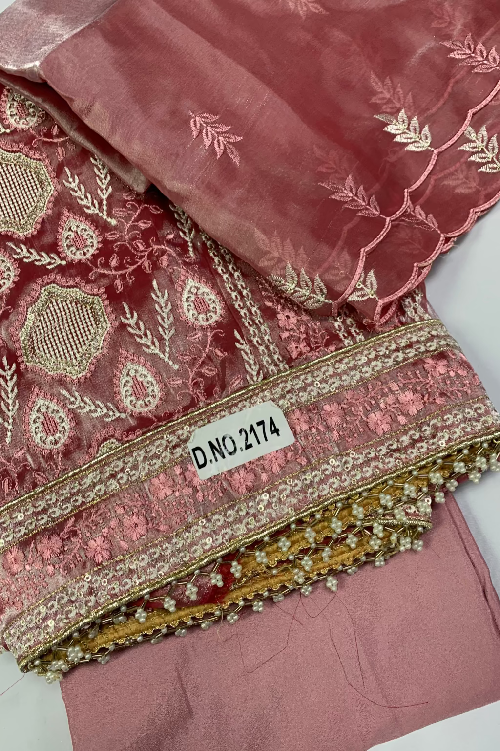 Pink embroidered fabric with a label on a white background