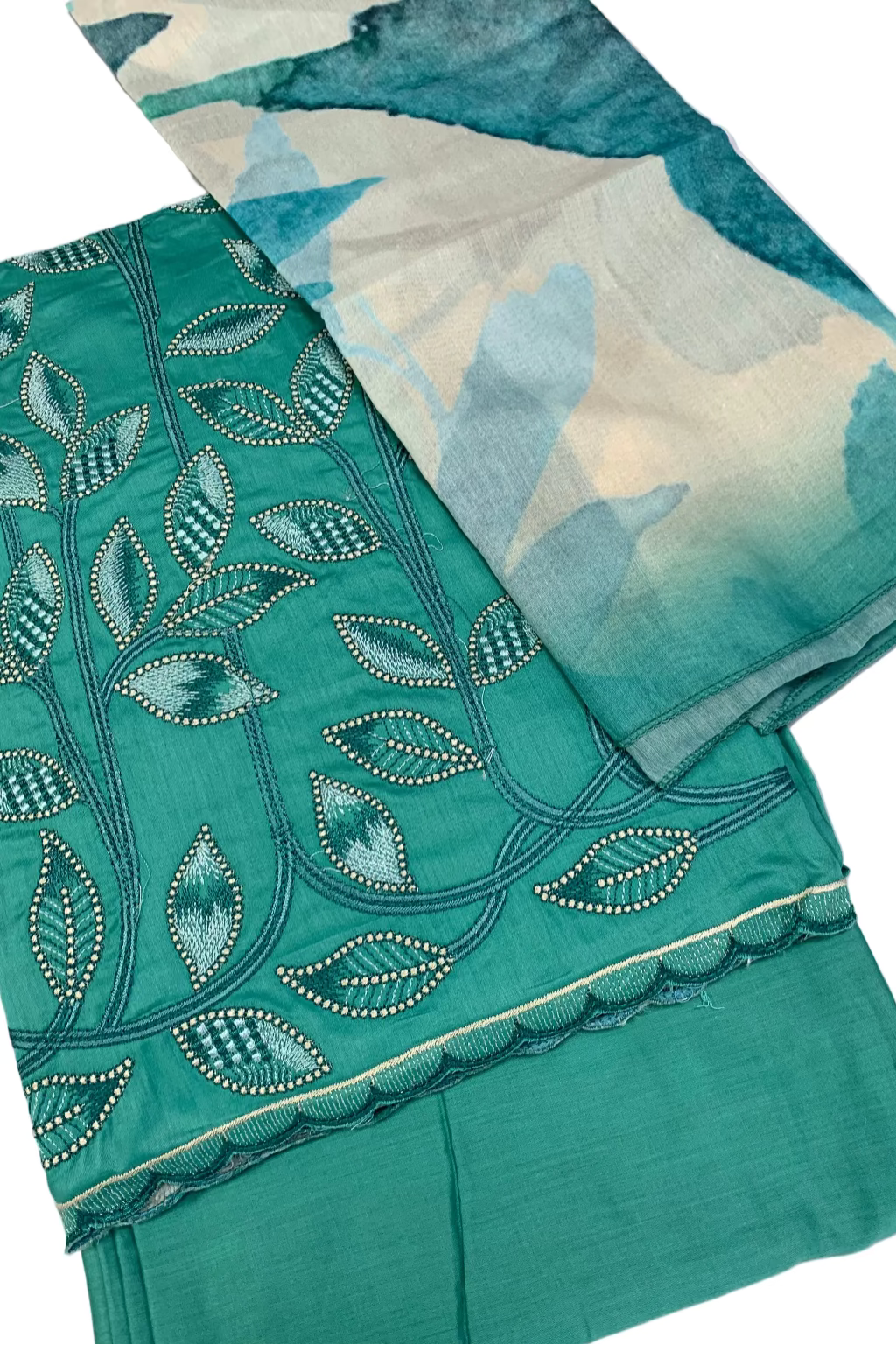 Teal fabric with intricate leaf patterns and beadwork on a white background