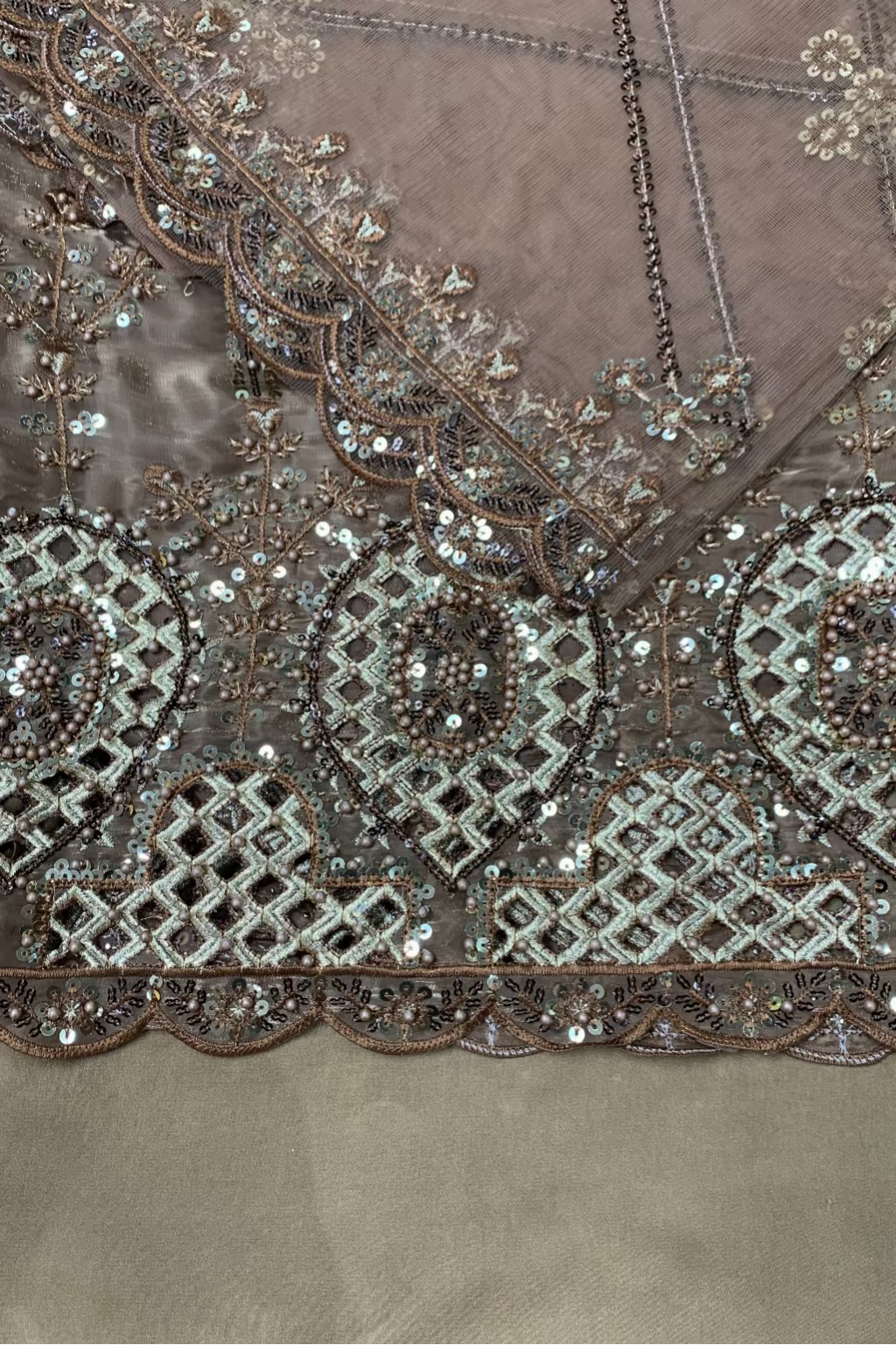Close-up of a brown fabric with intricate bead and sequin embroidery.