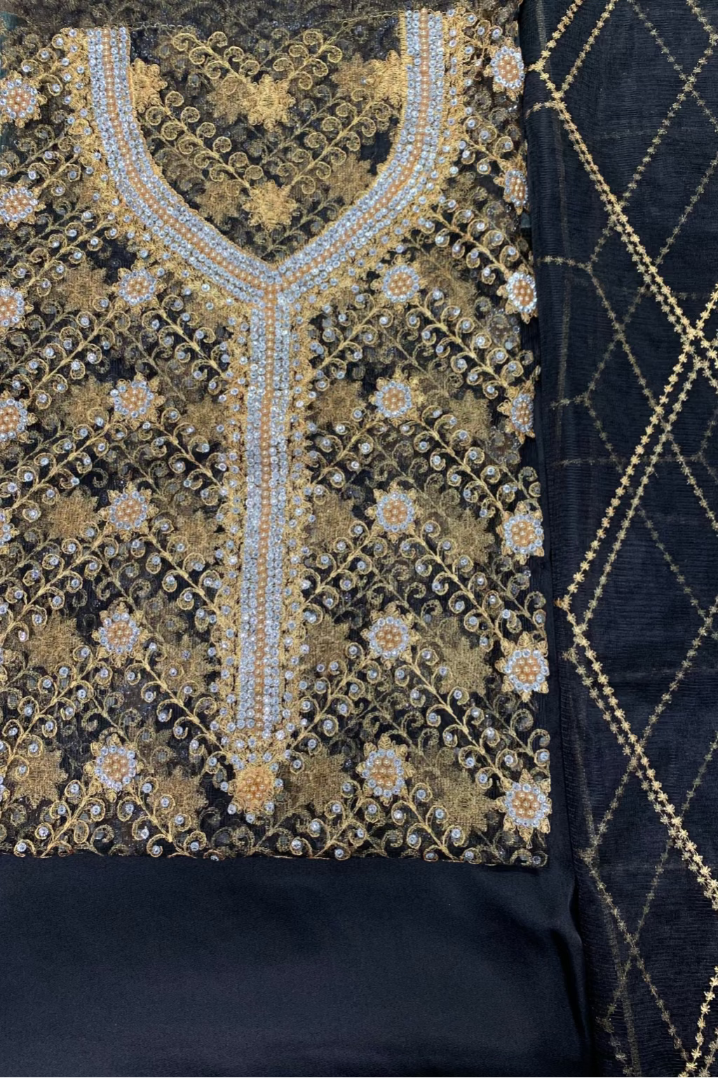 Black fabric with gold embroidery on a textured background