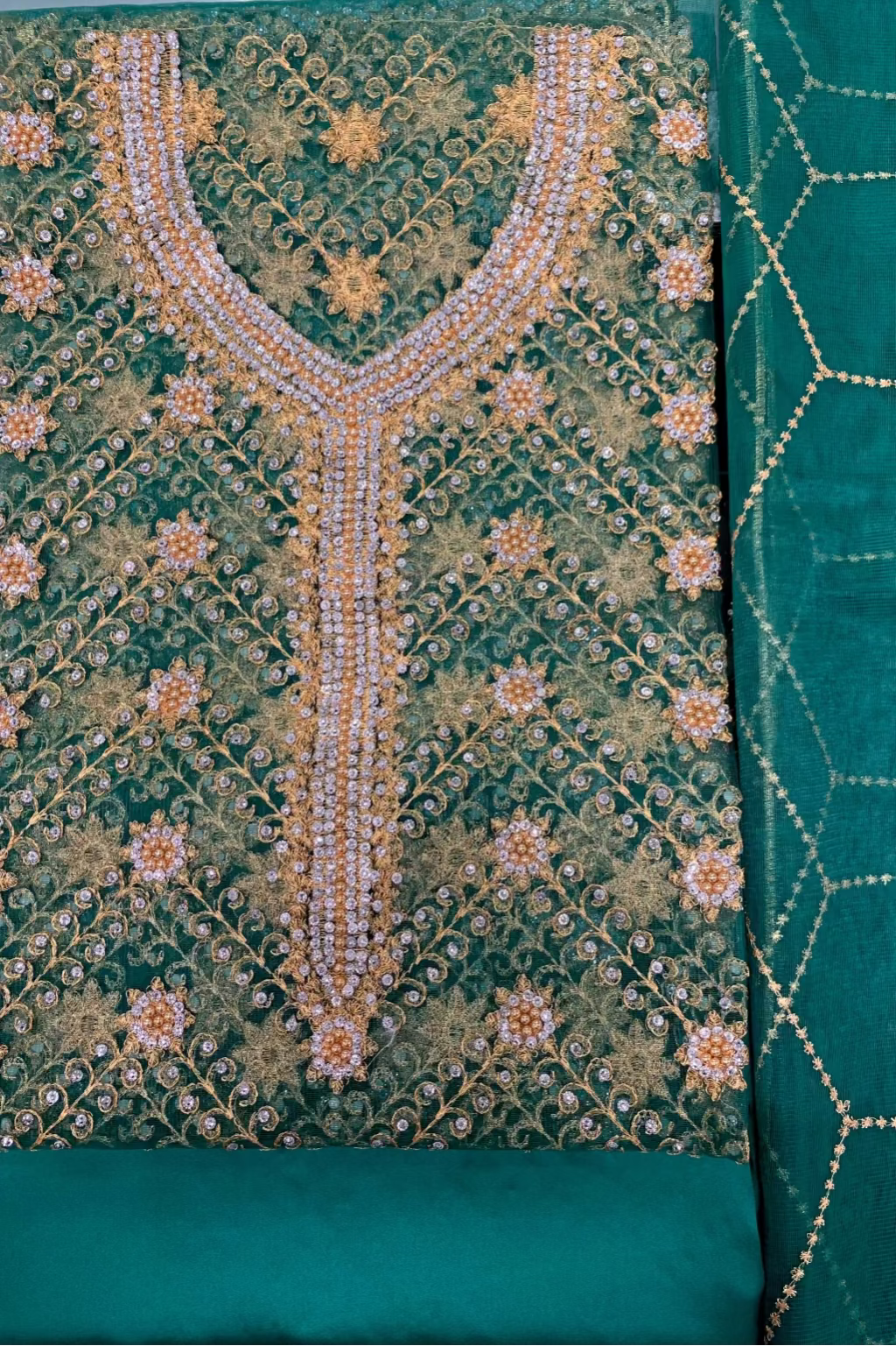 Teal fabric with intricate gold and white embroidery