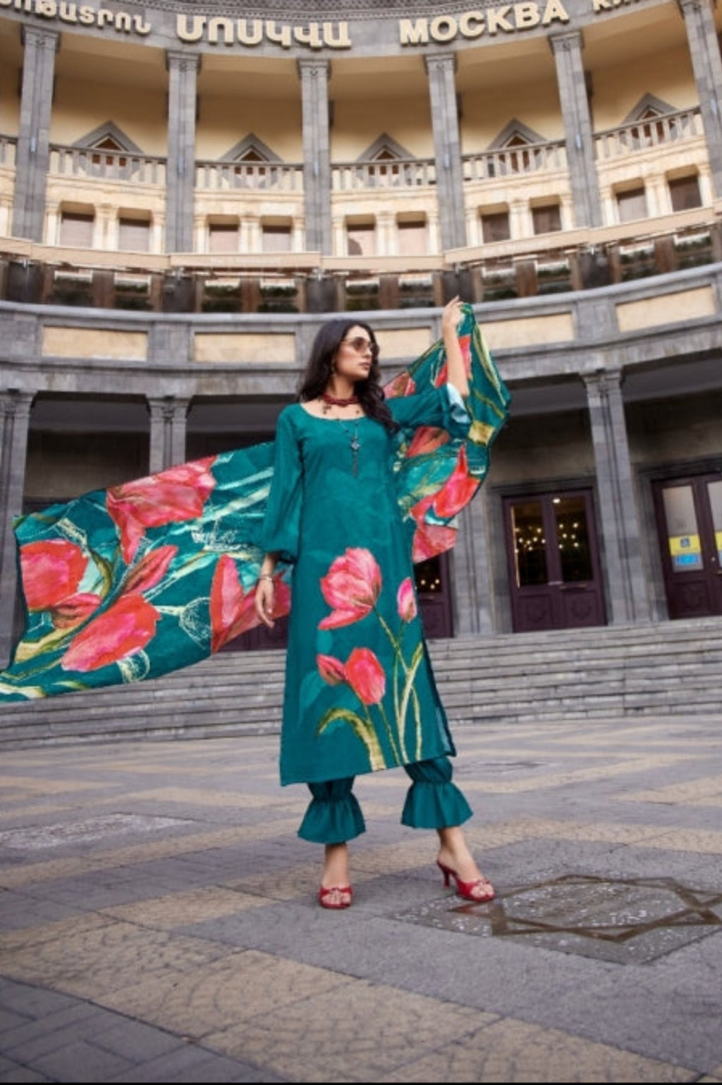 Woman in teal outfit with floral patterns in an outdoor setting