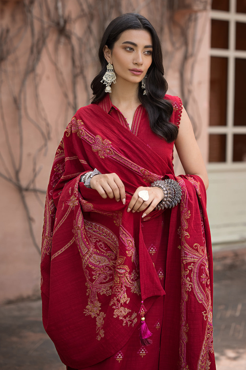 A woman wearing a red traditional salwar kameez suit with geometric patterns.