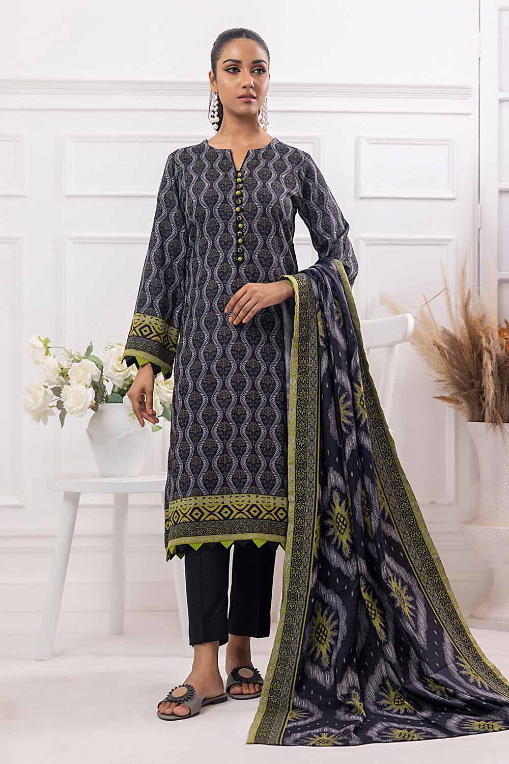 A woman modeling a gray and black printed Dhanak salwar kameez suit with a dupatta, shirt, and trousers from Gul Ahmed's winter collection.