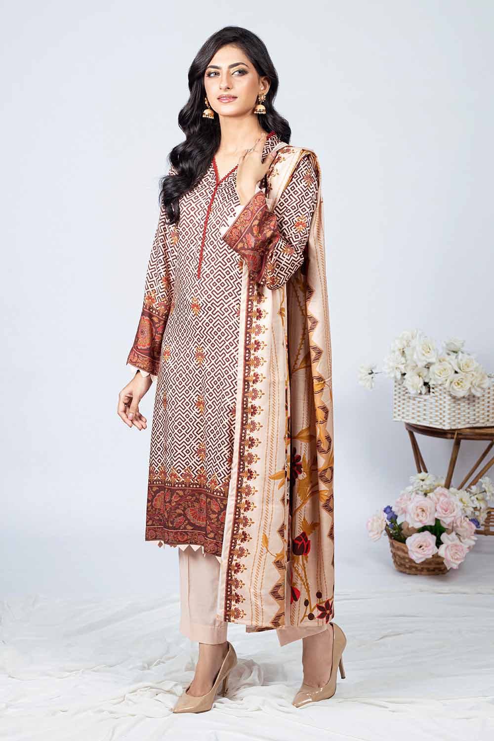 A woman modeling a beige and brown unstitched printed linen salwar kameez suit with embroidered details.