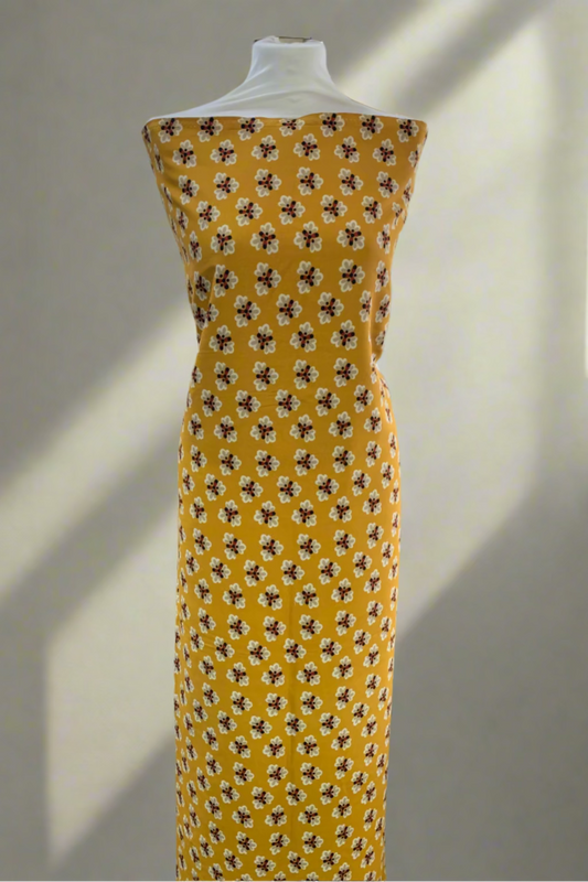 Yellow dress with black floral pattern on a mannequin in a store setting.