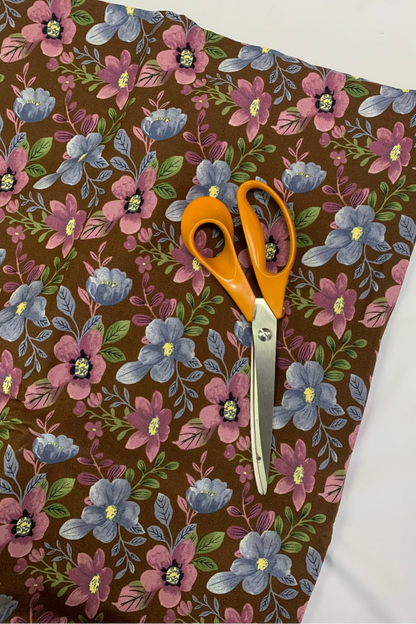 Floral-patterned fabric with orange-handled scissors on a white background