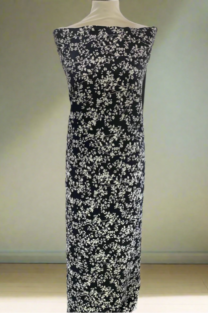 Black dress fabric with white floral pattern on a mannequin in a fabric store.