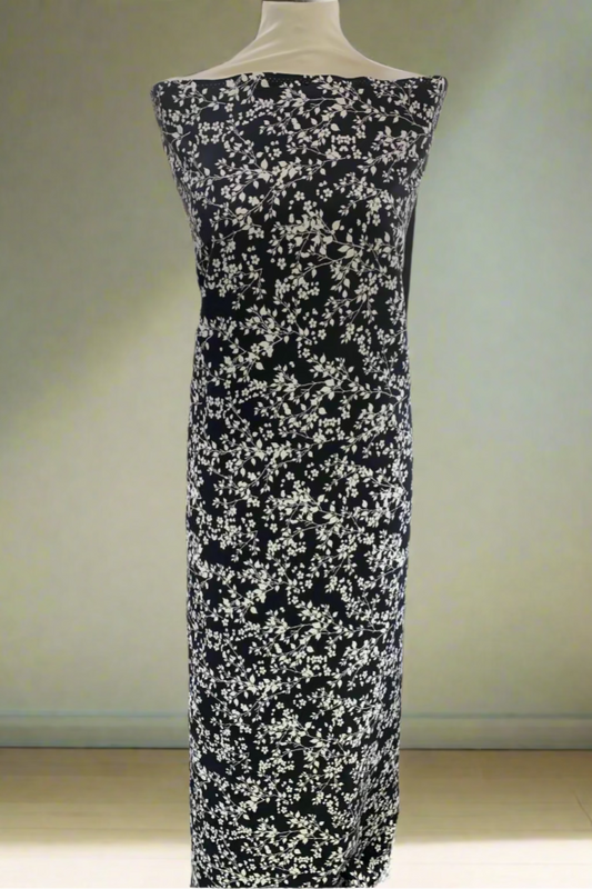 Black dress fabric with white floral pattern on a mannequin in a fabric store.