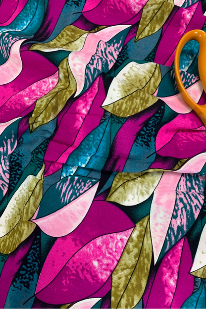 Colorful fabric with leaf pattern and orange scissors on top