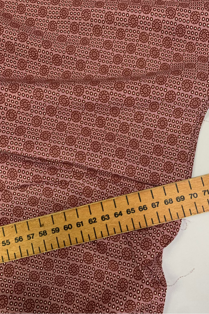 Soft pink fabric with a subtle pattern and a wooden measuring ruler on top
