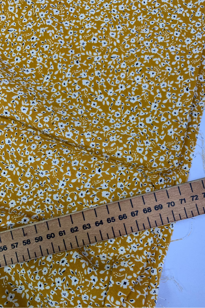 Yellow floral fabric with a ruler for scale on a white background